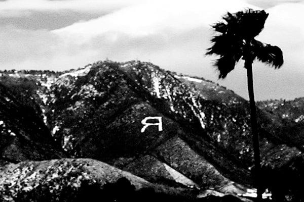 A black 和 white photograph of the mountains above 雷德兰兹 with the letter R on the side of a mountain